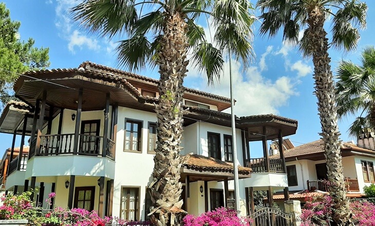 Akyaka’daki geleneksel Muğla mimarisiyle inşa edilmiş beyaz badanalı ev ve palmiye ağaçları